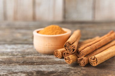 Seylan tarçın. Tarçın ahşap bir zemine yapışır. Tarçın rulosu ve pudra. Fırın, tatlı ve içecekler için baharatlı baharat. Güzel kokulu tarçın. Yakın plan. Mesaj için yer. Boşluğu kopyala