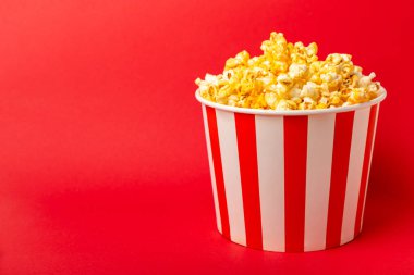 Patlamış mısır kutusu. Kırmızı ve beyaz çizgili patlamış mısır kovaları. Sinema ve eğlence anlayışı. Patlamış mısırla film gecesi. Peynirli patlamış mısır. Lezzetli aperatif, aperatif. Metin için yer.