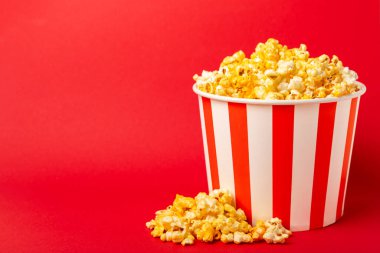 Patlamış mısır kutusu. Kırmızı ve beyaz çizgili patlamış mısır kovaları. Sinema ve eğlence anlayışı. Patlamış mısırla film gecesi. Peynirli patlamış mısır. Lezzetli aperatif, aperatif. Metin için yer.
