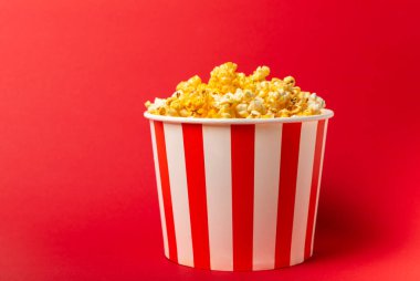 Patlamış mısır kutusu. Kırmızı ve beyaz çizgili patlamış mısır kovaları. Sinema ve eğlence anlayışı. Patlamış mısırla film gecesi. Peynirli patlamış mısır. Lezzetli aperatif, aperatif. Metin için yer.