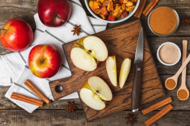 Tarçınlı elmalar ahşap kaplamalı. Tarçın çubukları ve yıldız anason ile kokulu kırmızı elmalar. Baharatlı elma dilimleri. Mesaj için yer. Uzayı kopyala Hasat. Meyveler.