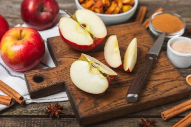 Tarçınlı elmalar ahşap kaplamalı. Tarçın çubukları ve yıldız anason ile kokulu kırmızı elmalar. Baharatlı elma dilimleri. Mesaj için yer. Uzayı kopyala Hasat. Meyveler.