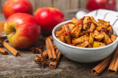 Tarçınlı elmalar ahşap kaplamalı. Tarçın çubukları ve yıldız anason ile kokulu kırmızı elmalar. Baharatlı elma dilimleri. Mesaj için yer. Uzayı kopyala Hasat. Meyveler.