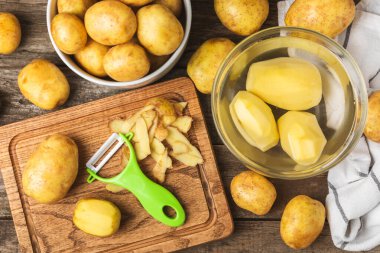 Genç patatesler Ahşap zeminde çiğ patates ve bıçak. Patates soy. Hasat topla. organik, taze kazılmış patatesler. Tarım geçmişi. Vejetaryen. Sebzeler. Mesajlar için yer. Boşluğu kopyala