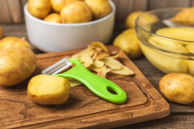 Genç patatesler Ahşap zeminde çiğ patates ve bıçak. Patates soy. Hasat topla. organik, taze kazılmış patatesler. Tarım geçmişi. Vejetaryen. Sebzeler. Mesajlar için yer. Boşluğu kopyala