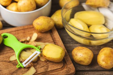 Genç patatesler Ahşap zeminde çiğ patates ve bıçak. Patates soy. Hasat topla. organik, taze kazılmış patatesler. Tarım geçmişi. Vejetaryen. Sebzeler. Mesajlar için yer. Boşluğu kopyala