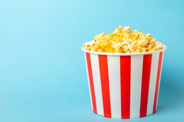 Patlamış mısır kutusu. Mavi arka planda kırmızı ve beyaz çizgili patlamış mısır kovaları. Sinema ve eğlence anlayışı. Patlamış mısırla film gecesi. Peynirli patlamış mısır. Lezzetli aperatif, aperatif. Metin için yer.