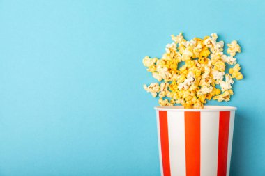 Patlamış mısır kutusu. Mavi arka planda kırmızı ve beyaz çizgili patlamış mısır kovaları. Sinema ve eğlence anlayışı. Patlamış mısırla film gecesi. Peynirli patlamış mısır. Lezzetli aperatif, aperatif. Metin için yer.