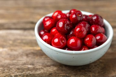 Kirazlar. Ahşap kaplamalı taze kirazlar ve yapraklar. Taze organik kiraz yığını. Böğürtlen ve meyve. Vejetaryen. Sağlıklı beslenme. Mesaj için yer. Boşluğu kopyala