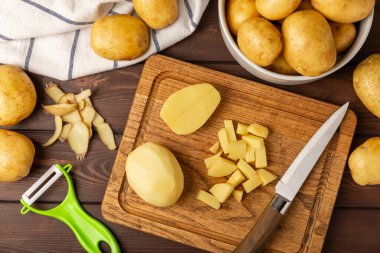 Genç patatesler Ahşap zeminde çiğ patates ve bıçak. Patates soy. Hasat topla. organik, taze kazılmış patatesler. Tarım geçmişi. Vejetaryen. Sebzeler. Mesajlar için yer. Boşluğu kopyala