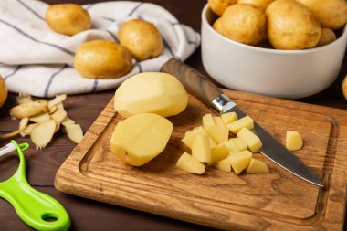 Genç patatesler Ahşap zeminde çiğ patates ve bıçak. Patates soy. Hasat topla. organik, taze kazılmış patatesler. Tarım geçmişi. Vejetaryen. Sebzeler. Mesajlar için yer. Boşluğu kopyala