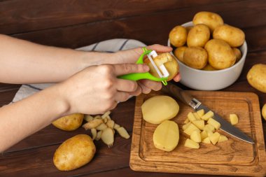 Genç patatesler Ahşap zeminde çiğ patates ve bıçak. Patates soy. Hasat topla. organik, taze kazılmış patatesler. Tarım geçmişi. Vejetaryen. Sebzeler. Mesajlar için yer. Boşluğu kopyala