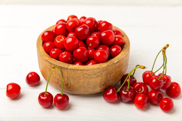 Cherries. Fresh ripe cherries with leaves on a textured wooden background. Fresh sweet organic cherry pile. Berries and fruits. Vegan. Healthy eating. Place for text. Copy space