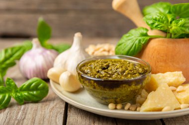 Pesto. Ahşap kaplamalı İtalyan fesleğen sosu. Pesto sosu içeriği: taze fesleğen, çam fıstığı, parmesan peyniri ve zeytinyağı. Metin için boşluk. Boşluğu kopyala.