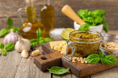 Pesto. Ahşap kaplamalı İtalyan fesleğen sosu. Pesto sosu içeriği: taze fesleğen, çam fıstığı, parmesan peyniri ve zeytinyağı. Metin için boşluk. Boşluğu kopyala.