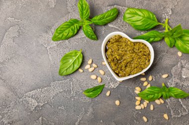 Pesto. Ahşap kaplamalı İtalyan fesleğen sosu. Pesto sosu içeriği: taze fesleğen, çam fıstığı, parmesan peyniri ve zeytinyağı. Metin için boşluk. Boşluğu kopyala.