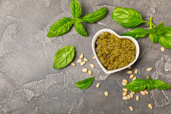 Pesto. Ahşap kaplamalı İtalyan fesleğen sosu. Pesto sosu içeriği: taze fesleğen, çam fıstığı, parmesan peyniri ve zeytinyağı. Metin için boşluk. Boşluğu kopyala.