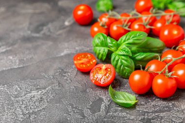 Taze vişneli domates ve dokulu taze yeşil fesleğen. Domates sosu. Vejetaryen. Salata için malzemeler. Organik yiyecekler. Mesaj için yer. Boşluğu kopyala.