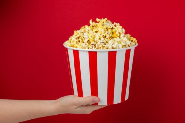 Patlamış mısır kutusu. Kırmızı ve beyaz çizgili kırmızı arka planda tuzlu patlamış mısır kovaları. Sinema ve eğlence anlayışı. Patlamış mısırla film gecesi. Lezzetli aperatif, aperatif. Metin için yer.