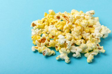 Mavi arka planda tuzlu patlamış mısır. Sinema ve eğlence anlayışı. Patlamış mısırla film gecesi. Lezzetli aperatif, aperatif. Mesaj için yer. Uzayı kopyala Pankart