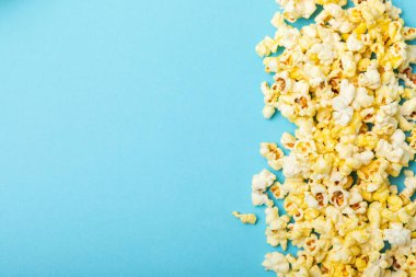 Mavi arka planda tuzlu patlamış mısır. Sinema ve eğlence anlayışı. Patlamış mısırla film gecesi. Lezzetli aperatif, aperatif. Mesaj için yer. Uzayı kopyala Pankart