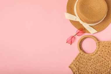 Plaj çantası, hasır şapka ve parlak renkli arka planda sandaletler. Plaj objesi. Yaz modasına uygun bir çanta. Plaj aksesuarları. Yaz tatili konsepti. Mesaj için uygun bir yer. Boşluğu kopyala. Üst görünüm