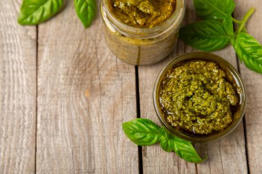 Pesto. Ahşap kaplamalı İtalyan fesleğen sosu. Pesto sosu içeriği: taze fesleğen, çam fıstığı, parmesan peyniri ve zeytinyağı. Metin için boşluk. Boşluğu kopyala.