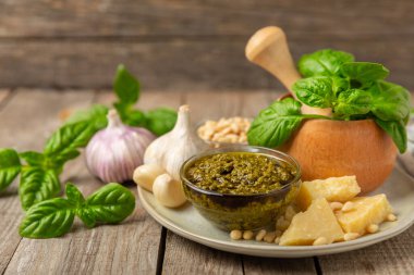 Pesto. Ahşap kaplamalı İtalyan fesleğen sosu. Pesto sosu içeriği: taze fesleğen, çam fıstığı, parmesan peyniri ve zeytinyağı. Metin için boşluk. Boşluğu kopyala.