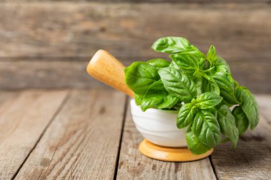 Ahşap kaplamalı havanda taze yeşil fesleğen. Organik baharatlar ve bitkiler. Vejetaryen. Taze mutfak bitkileri. Fesleğen taze fesleğen havan ve kabuklu pesto 'ya dönüştürülüyor. Boşluğu kopyala. Metin için yer