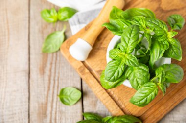 Ahşap kaplamalı havanda taze yeşil fesleğen. Organik baharatlar ve bitkiler. Vejetaryen. Taze mutfak bitkileri. Fesleğen taze fesleğen havan ve kabuklu pesto 'ya dönüştürülüyor. Boşluğu kopyala. Metin için yer