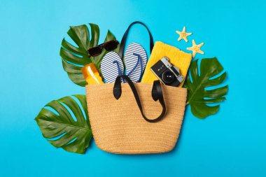 Plaj aksesuarları. Şapkalı plaj çantası, plaj havlusu, güneş gözlüğü, parlak renkli arka planda saç kremi ve sandaletler. Tropik tatil konsepti. Yaz haftasonu. Düz yatıyordu. Mesaj için yer var. Boşluğu kopyala