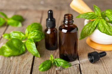 Ahşap kaplamalı fesleğen yağı. Fesleğen yağı ve taze yapraklar. Aromaterapi. Aroma yağı. Şifalı bitkiler. Alternatif tıp. Mesaj için yer. Boşluğu kopyala.