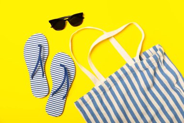 Plaj aksesuarları. Şapkalı plaj çantası, plaj havlusu, güneş gözlüğü, parlak renkli arka planda saç kremi ve sandaletler. Tropik tatil konsepti. Yaz haftasonu. Düz yatıyordu. Mesaj için yer var. Boşluğu kopyala