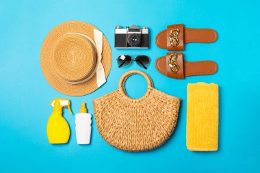 Plaj aksesuarları. Şapkalı plaj çantası, plaj havlusu, güneş gözlüğü, parlak renkli arka planda saç kremi ve sandaletler. Tropik tatil konsepti. Yaz haftasonu. Düz yatıyordu. Mesaj için yer var. Boşluğu kopyala