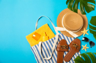 Plaj aksesuarları. Şapkalı plaj çantası, plaj havlusu, güneş gözlüğü, parlak renkli arka planda saç kremi ve sandaletler. Tropik tatil konsepti. Yaz haftasonu. Düz yatıyordu. Mesaj için yer var. Boşluğu kopyala