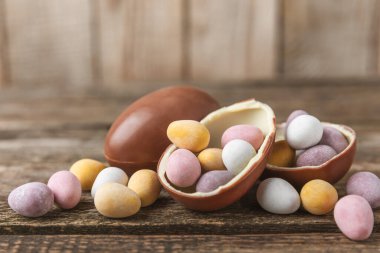 Renkli Paskalya yumurtası. Evet. Paskalya kutlaması. Mutlu Paskalyalar. Çikolatalı tatlı yumurta. Şekerler ahşap masanın üzerinde. Metin için boşluk. Boşluğu kopyala