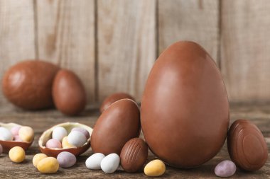 Arka planda paskalya çikolatalı yumurtası. Paskalya kutlaması. Paskalya çikolatalı tavşan. Çikolatalı tatlı yumurta. Şekerler ahşap masanın üzerinde. Mesaj için boşluk. Boşluğu kopyala. Hediye. Pankart.