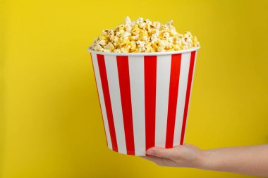 Patlamış mısır kutusu. Renkli arka planda kırmızı ve beyaz çizgili patlamış mısır kovaları. Sinema ve eğlence anlayışı. Patlamış mısırla film gecesi. Lezzetli aperatif, aperatif. Metin için yer.