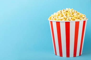 Patlamış mısır kutusu. Renkli arka planda kırmızı ve beyaz çizgili patlamış mısır kovaları. Sinema ve eğlence anlayışı. Patlamış mısırla film gecesi. Lezzetli aperatif, aperatif. Metin için yer.
