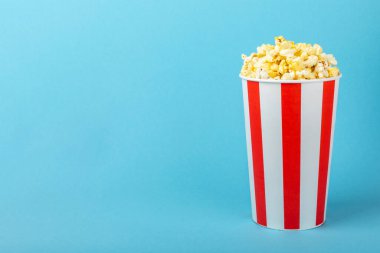 Patlamış mısır kutusu. Renkli arka planda kırmızı ve beyaz çizgili patlamış mısır kovaları. Sinema ve eğlence anlayışı. Patlamış mısırla film gecesi. Lezzetli aperatif, aperatif. Metin için yer.