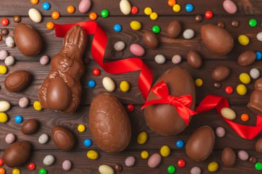 Arka planda paskalya çikolatalı yumurtası. Paskalya kutlaması. Paskalya çikolatalı tavşan. Çikolatalı tatlı yumurta. Şekerler ahşap masanın üzerinde. Mesaj için boşluk. Boşluğu kopyala. Hediye. Pankart.