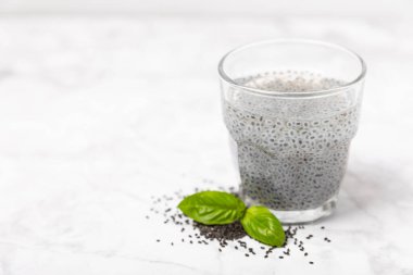 Dökümlü ahşap arka planda fesleğen ve fesleğen tohumu. Yakın plan. Süper yemek. Ocimum bazilika. Organik fesleğen tohumu. selasih. Vejetaryen içkisi. Mesaj için yer var. Boşluğu kopyala.