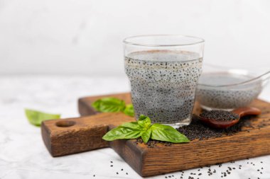 Dökümlü ahşap arka planda fesleğen ve fesleğen tohumu. Yakın plan. Süper yemek. Ocimum bazilika. Organik fesleğen tohumu. selasih. Vejetaryen içkisi. Mesaj için yer var. Boşluğu kopyala.