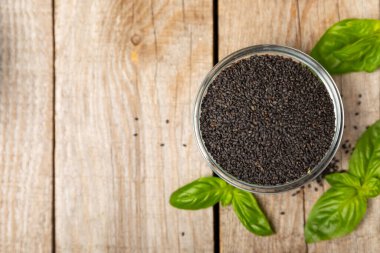 Dökümlü ahşap arka planda fesleğen tohumları. Yakın plan. Süper yemek. Ocimum bazilika. Organik fesleğen tohumu. selasih. Mesaj için yer var. Boşluğu kopyala.