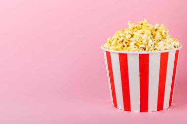 Patlamış mısır kutusu. Renkli arka planda kırmızı ve beyaz çizgili patlamış mısır kovaları. Sinema ve eğlence anlayışı. Patlamış mısırla film gecesi. Lezzetli aperatif, aperatif. Metin için yer.