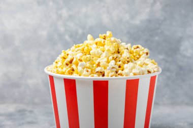 Patlamış mısır kutusu. Renkli arka planda kırmızı ve beyaz çizgili patlamış mısır kovaları. Sinema ve eğlence anlayışı. Patlamış mısırla film gecesi. Lezzetli aperatif, aperatif. Metin için yer.