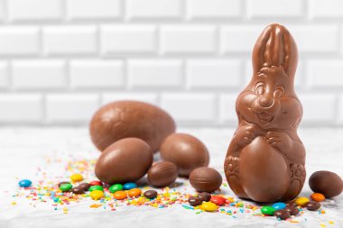 Arka planda paskalya çikolatalı yumurtası. Paskalya kutlaması. Paskalya çikolatalı tavşan. Çikolatalı tatlı yumurta. Şekerler ahşap masanın üzerinde. Mesaj için boşluk. Boşluğu kopyala. Hediye. Pankart.