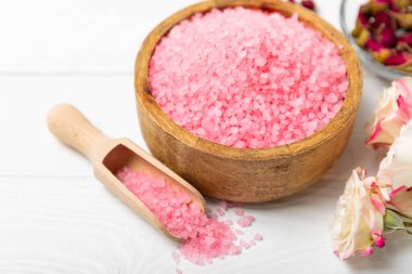 Banyo için deniz tuzu aromalı ve ahşap kaplamalı gül çiçekli. Pembe deniz tuzu. Spa tedavileri. Doğal tuz, bitkiler ve gerekli yağlar. Cilt bakımı. Mesaj için Meso. Boşluğu kopyala