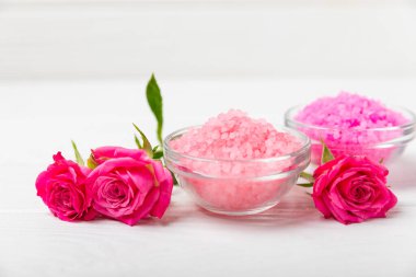 Banyo için deniz tuzu aromalı ve ahşap kaplamalı gül çiçekli. Pembe deniz tuzu. Spa tedavileri. Doğal tuz, bitkiler ve gerekli yağlar. Cilt bakımı. Mesaj için Meso. Boşluğu kopyala