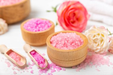Banyo için deniz tuzu aromalı ve ahşap kaplamalı gül çiçekli. Pembe deniz tuzu. Spa tedavileri. Doğal tuz, bitkiler ve gerekli yağlar. Cilt bakımı. Mesaj için Meso. Boşluğu kopyala